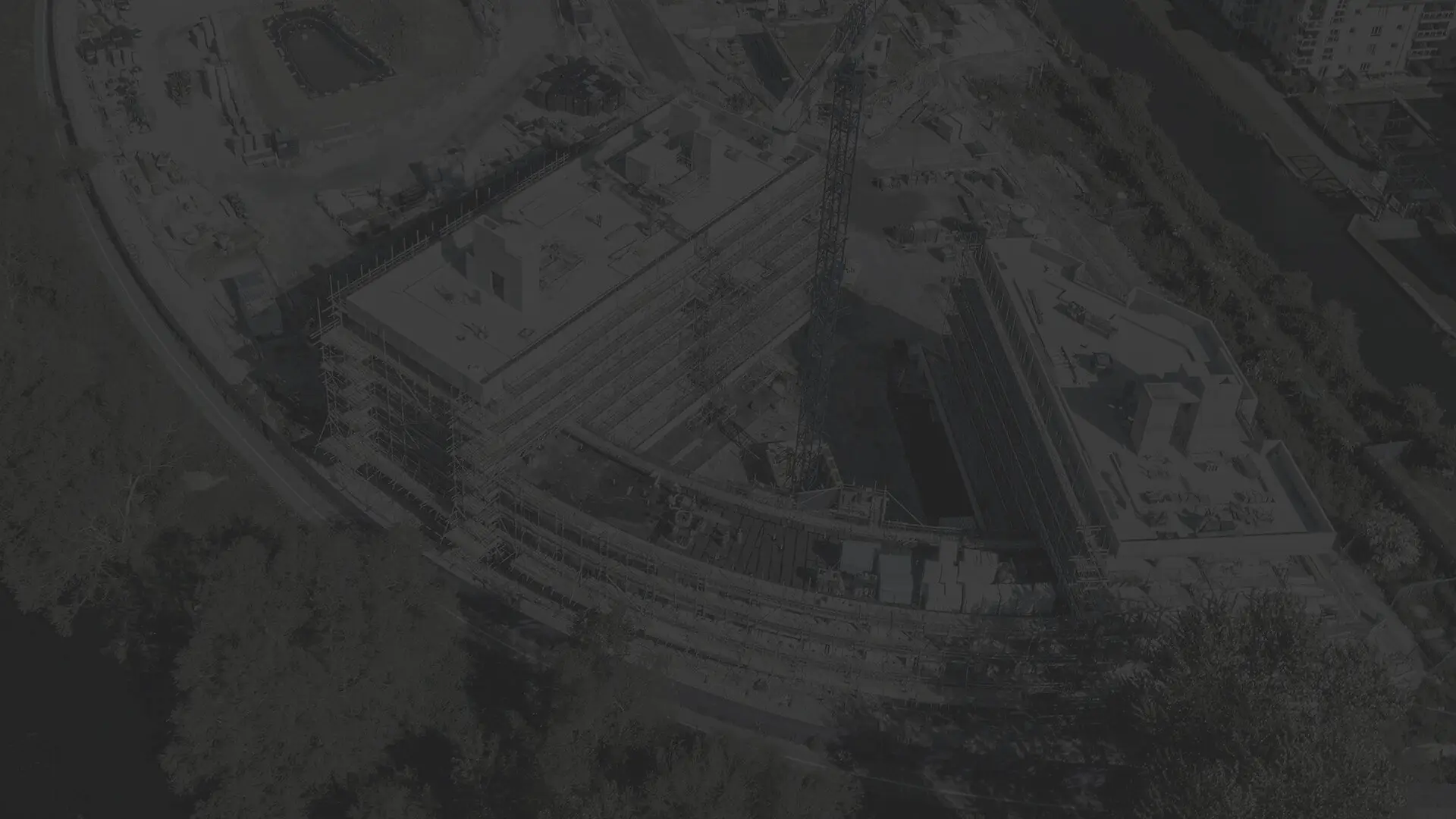 A dark tinted aerial photo of a large modern building under construction